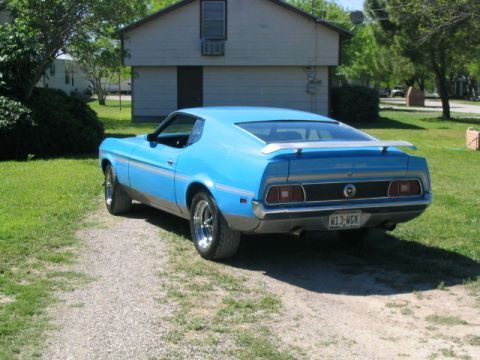 1972 Ford Mustang - A blue 1971 Ford Mustang coupe is parked on a gravel driveway in front of a house.