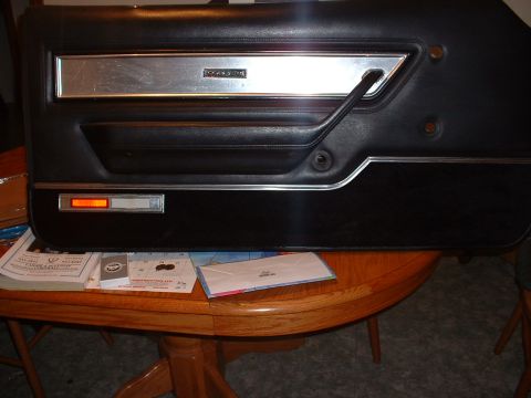 1978 Ford Mustang II - A car door panel with a "COUGAR" emblem is shown resting on a table with papers.