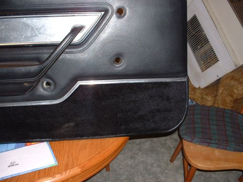 1978 Ford Mustang II - Close-up of a black interior door panel, likely from a classic car, chrome accents and a pull handle.