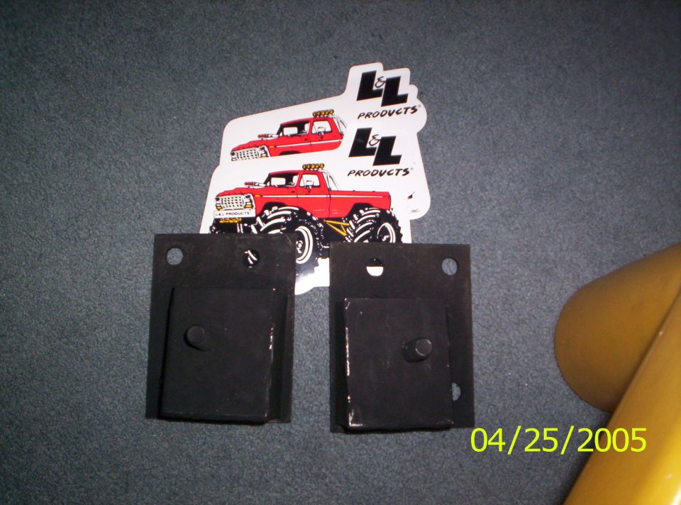 Two black metal brackets and two stickers of red monster trucks with LL Products branding