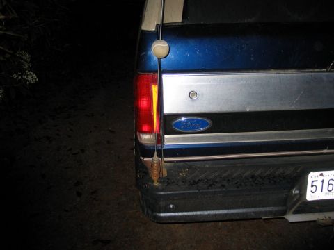 1995 Ford Bronco - The rear of a blue and silver Ford Bronco is shown at night, with a tennis ball on its antenna.
