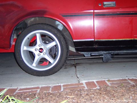 1971 Ford Mustang - Side view of a red car with a black stripe and aftermarket wheels.