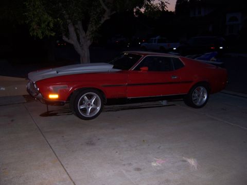 1971 Ford Mustang - Side view of a red 1971 Ford Mustang coupe with a silver hood, parked outdoors.