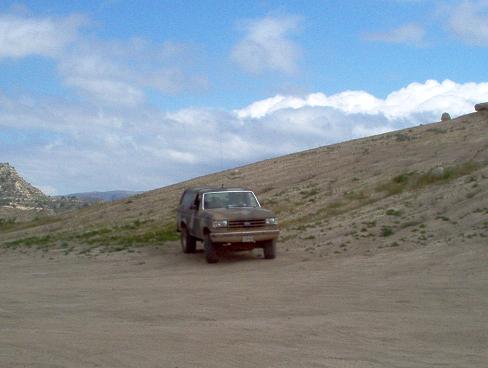 Brown 1988 Ford Bronco on dirt hill under cloudy sky