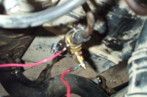 1988 Ford Bronco - A close-up view of a brass fitting and wiring, likely a sensor or valve, within a vehicle's engine bay.
