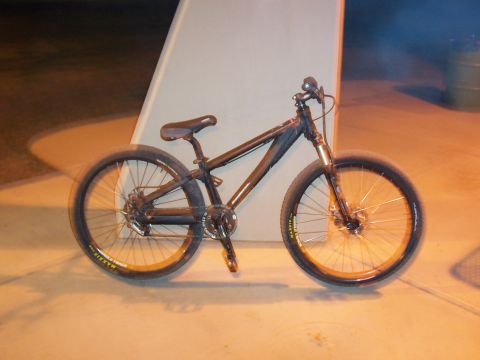 1994 Ford Bronco - A black dirt jump bicycle with gold accents is parked outdoors at night, illuminated by artificial lights.