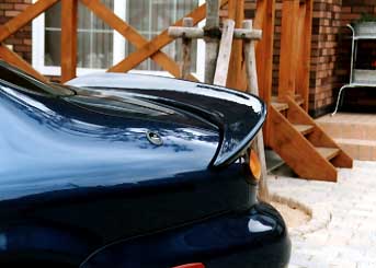 1999 Ford Taurus - Close-up of a car's rear spoiler, showing a water droplet on its surface.