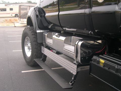 1989 Ford Bronco - A close-up view of the side of a large black truck, highlighting its fuel tanks and steps.