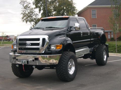 1989 Ford Bronco - This black Ford F-Series truck is shown from a three-quarter front view, highlighting its lifted suspension and large tires.