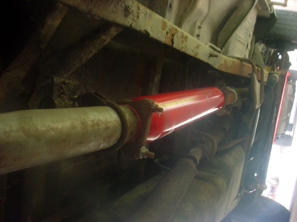 Underside view of a red exhaust muffler and pipe attached to a vehicle's frame