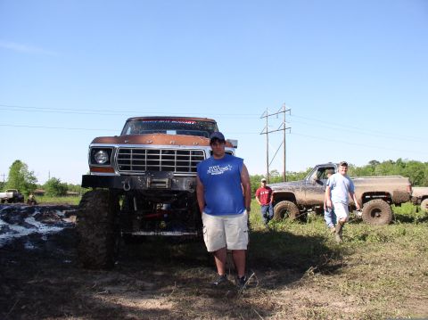 2000 Chevrolet Tahoe - A lifted Ford truck is parked in a muddy field, with people standing around it.
