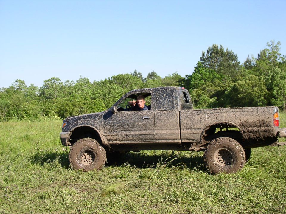 Mud-covered pickup truck driving through a grassy field