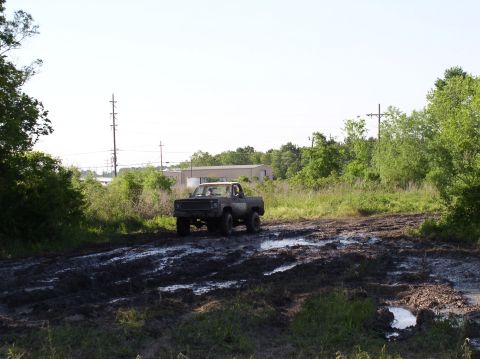 2000 Chevrolet Tahoe - Pickup truck navigating a challenging muddy terrain on a sunny day.