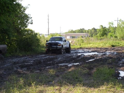 2000 Chevrolet Tahoe - A white pickup truck navigates a muddy track with visible tire ruts and puddles.