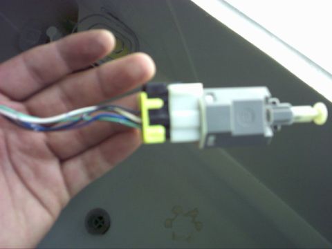 1997 Ford Probe - A close-up view of a vehicle's electrical connector with wires being held by a hand.