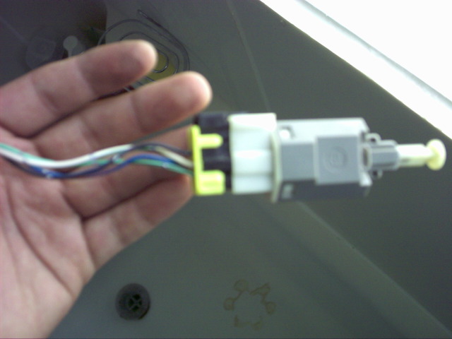 Hand holding a gray and white electrical connector with multiple colored wires attached