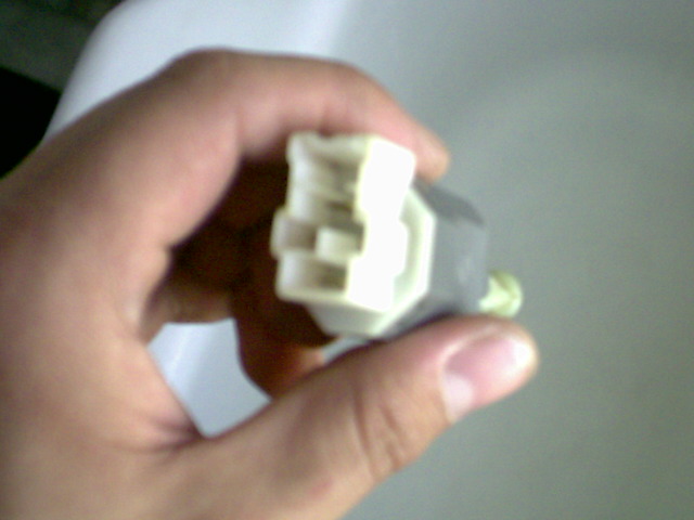 Hand holding a white and gray electrical connector with multiple pins