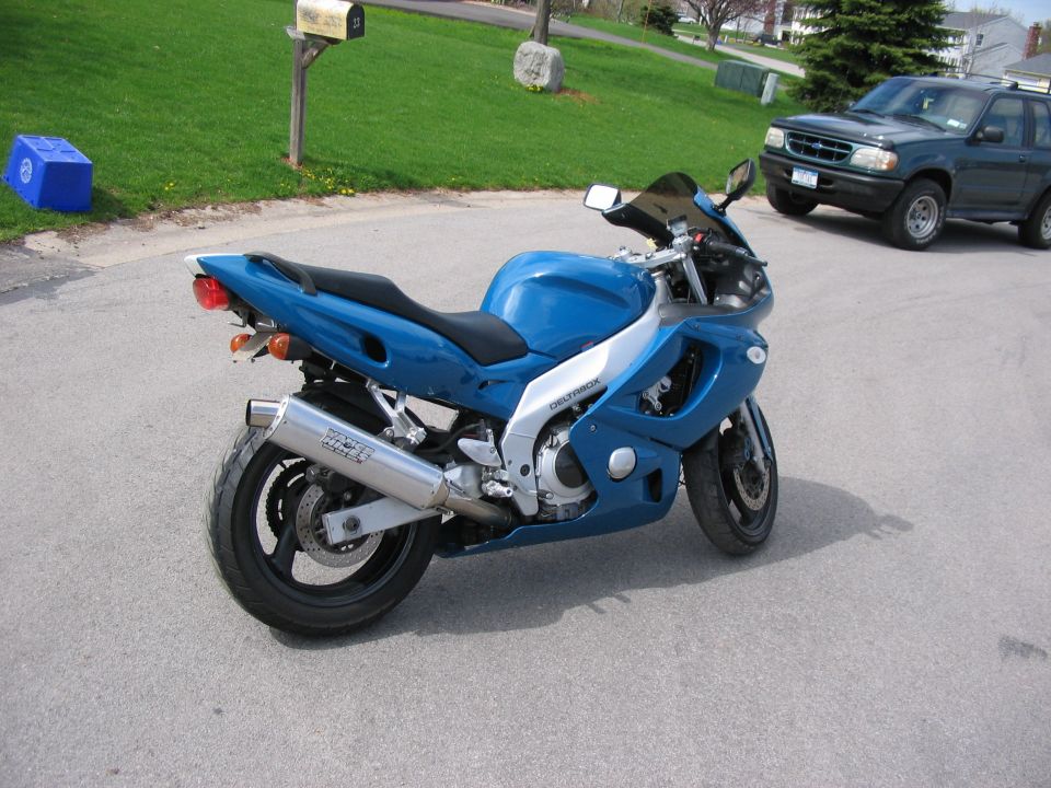 Blue Yamaha Deltabox sportbike with chrome slip-on exhaust parked in a driveway, rear three-quarter view