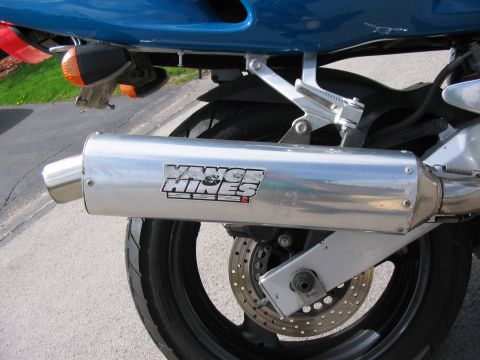 1997 Yamaha YT60 Tri-Moto - Close-up of a motorcycle's Vance & Hines exhaust system, showing the rear wheel and brake components.
