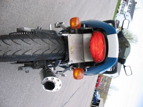 1997 Yamaha YT60 Tri-Moto - The rear section of a motorcycle is visible, including its tire, exhaust pipe, and tail light assembly.