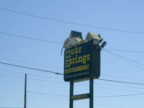 2000 Ford Crown Victoria - A sign for Clear Springs Restaurant, a large catfish graphic and advertising seafood and steaks.