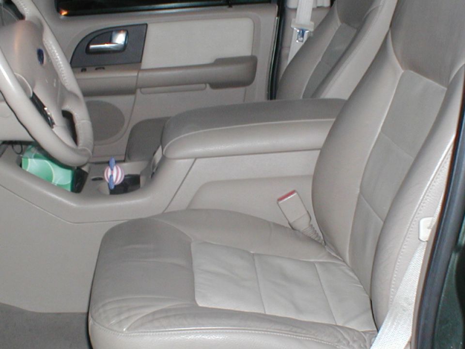 Interior shot of a vehicle's front passenger seat, center console, and dashboard area. Includes a tissue box and air freshener