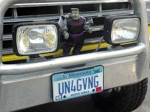 1988 Ford Bronco - A toy figure is placed on the front of a vehicle, obscuring the grille and part of the bumper.