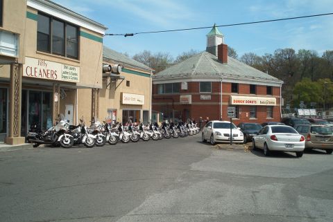 1992 Ford Taurus - Motorcycles and cars parked outside businesses on a sunny day.