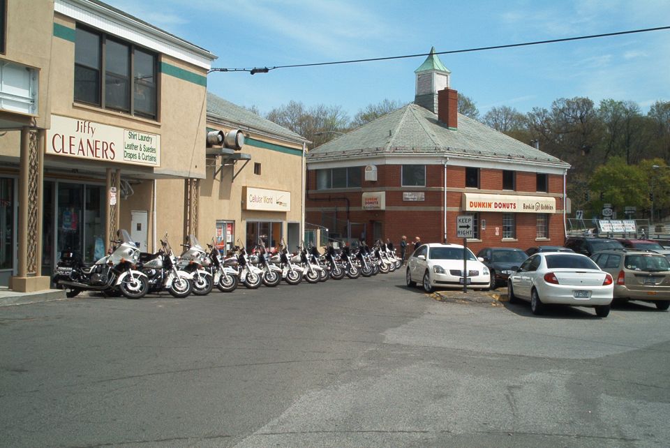 Row of parked motorcycles and cars in front of Jiffy Cleaners and Dunkin' Donuts