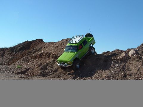 1988 Jeep Cherokee - A green Jeep Cherokee navigates a steep dirt incline under a clear blue sky.