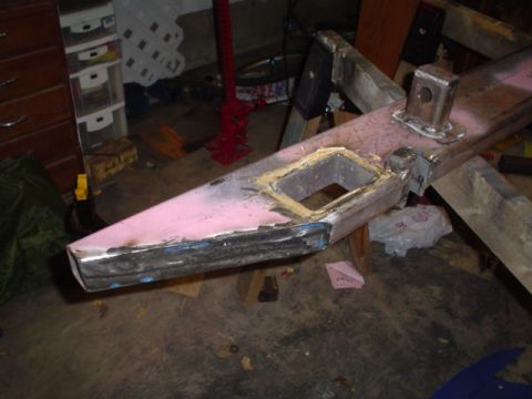 1981 Ford Bronco - A shop-fabricated steel bumper resting on sawhorses in a garage, its pink-primered face skim-coated with body filler around a square shackl…