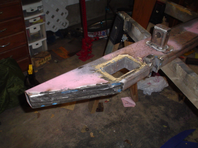 Fabricated pink-primered bumper with body filler and receiver tube on sawhorses