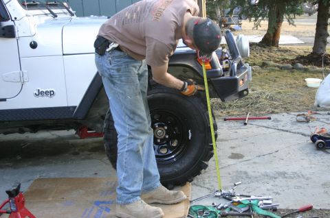2003 Jeep TJ - A person is using a tape measure to check the tire height on a Jeep Wrangler.