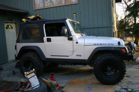 2003 Jeep TJ - Side view of a silver 2003 Jeep TJ Rubicon with a black soft top, parked in a driveway.