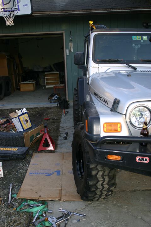 2003 Jeep TJ - A silver Jeep Wrangler is parked in front of a garage with tools and a jack nearby.