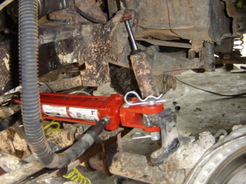 1989 Ford Bronco - Vehicle suspension work in progress with a hydraulic jack attached.
