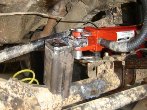 1989 Ford Bronco - Close-up view of a modified suspension part on a vehicle, a red hydraulic cylinder.