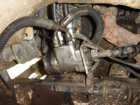 1989 Ford Bronco - Close-up view of a vehicle's power steering gearbox, showing hydraulic hoses and the connection to the steering shaft.