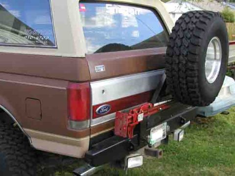 1988 Ford Bronco - Rear view of a 1988 Ford Bronco, showing the spare tire, a Hi-Lift jack, and a Ford emblem.