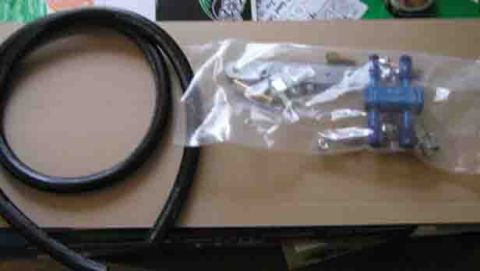1988 Ford Bronco - A blue plastic part and a black hose are shown in packaging on a cardboard surface.