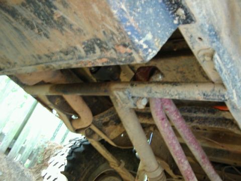 1985 Ford Bronco - Close-up view of the undercarriage of a dirty vehicle, showing suspension and exhaust components.