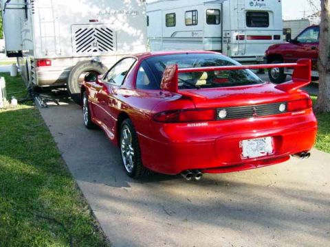 1999 Mitsubishi 3000GT - Rear view of a red 1999 Mitsubishi 3000GT sports car, parked next to an RV.
