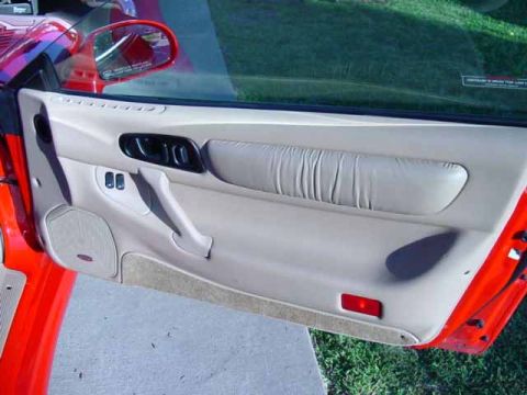 1999 Mitsubishi 3000GT - Close-up of a car's interior door panel, showing the armrest, door handle, and window controls.