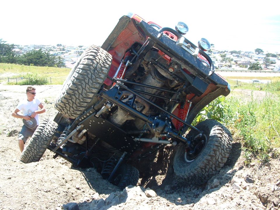 Off-road vehicle on its side in dirt with a person standing nearby