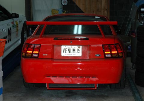 2000 Ford Mustang - Rear view of a red Ford Mustang SVT Cobra with a large rear spoiler and custom license plate.