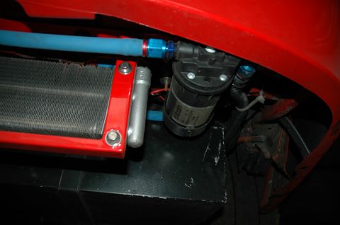 2000 Ford Mustang - Close-up view of a red car part a cooler, blue hose, and a black pump.