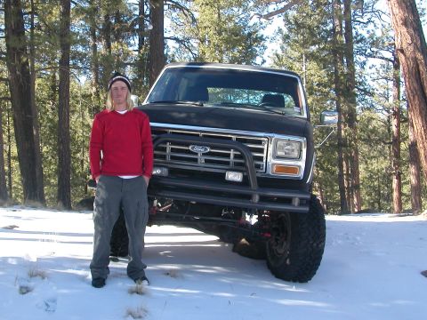 1984 Ford Bronco - A man poses in front of a lifted black Ford Bronco in a snowy forest setting.