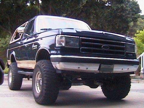 1991 Ford Bronco - This lifted 1992 Ford Bronco has a dark grille and chrome bumper, with large off-road tires.