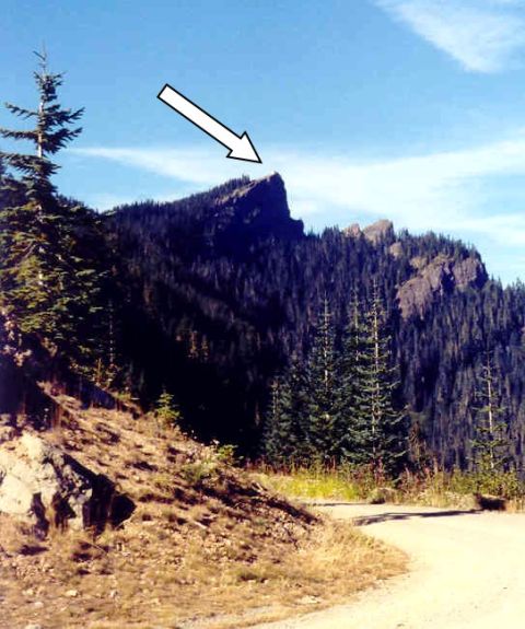 1976 Ford F-150 - A dirt road winds through a mountainous landscape with a prominent peak highlighted by an arrow.