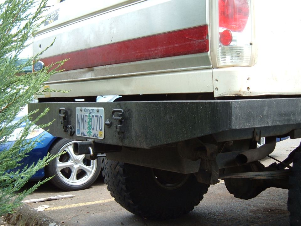 Rear view of a Ford Bronco with a custom bumper and Oregon license plate WMF 070. A blue car is visible to the left